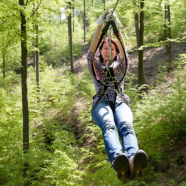 Frau an der Zipline im Wald